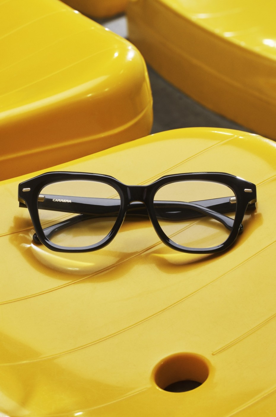Carrera: Schwarze Brille auf gelbem Stuhl